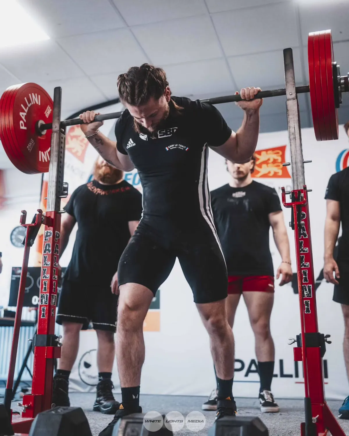 Un athlète prépare un squat lors d'une compétition de powerlifting. Photo @leo_coachsportif / @whitelightsmediafr.